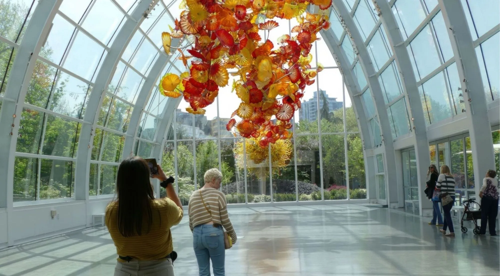 Visitors photographing the suspended ceiling sculpture in the daylit Glasshouse