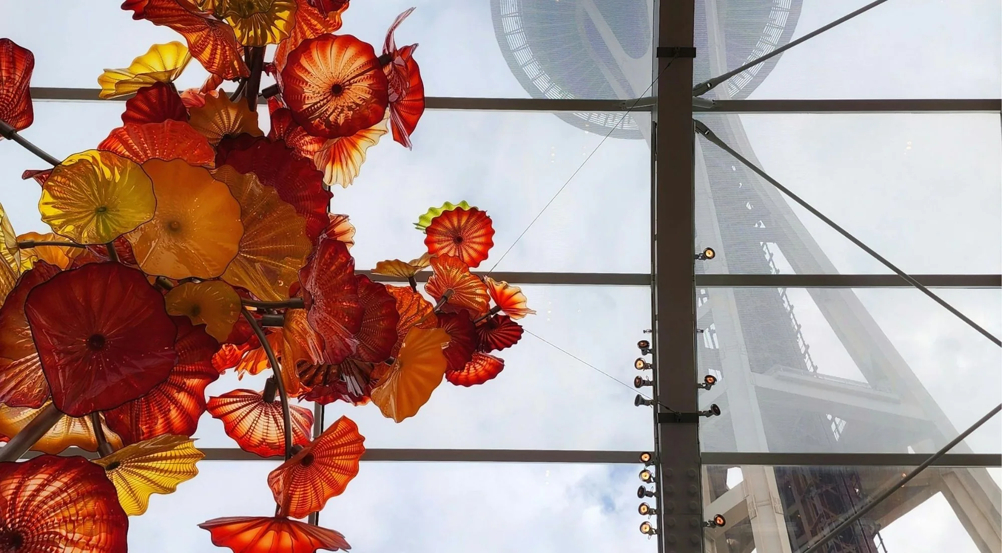 Red and amber glass forms under the Glasshouse roof with the Space Needle beyond the glass