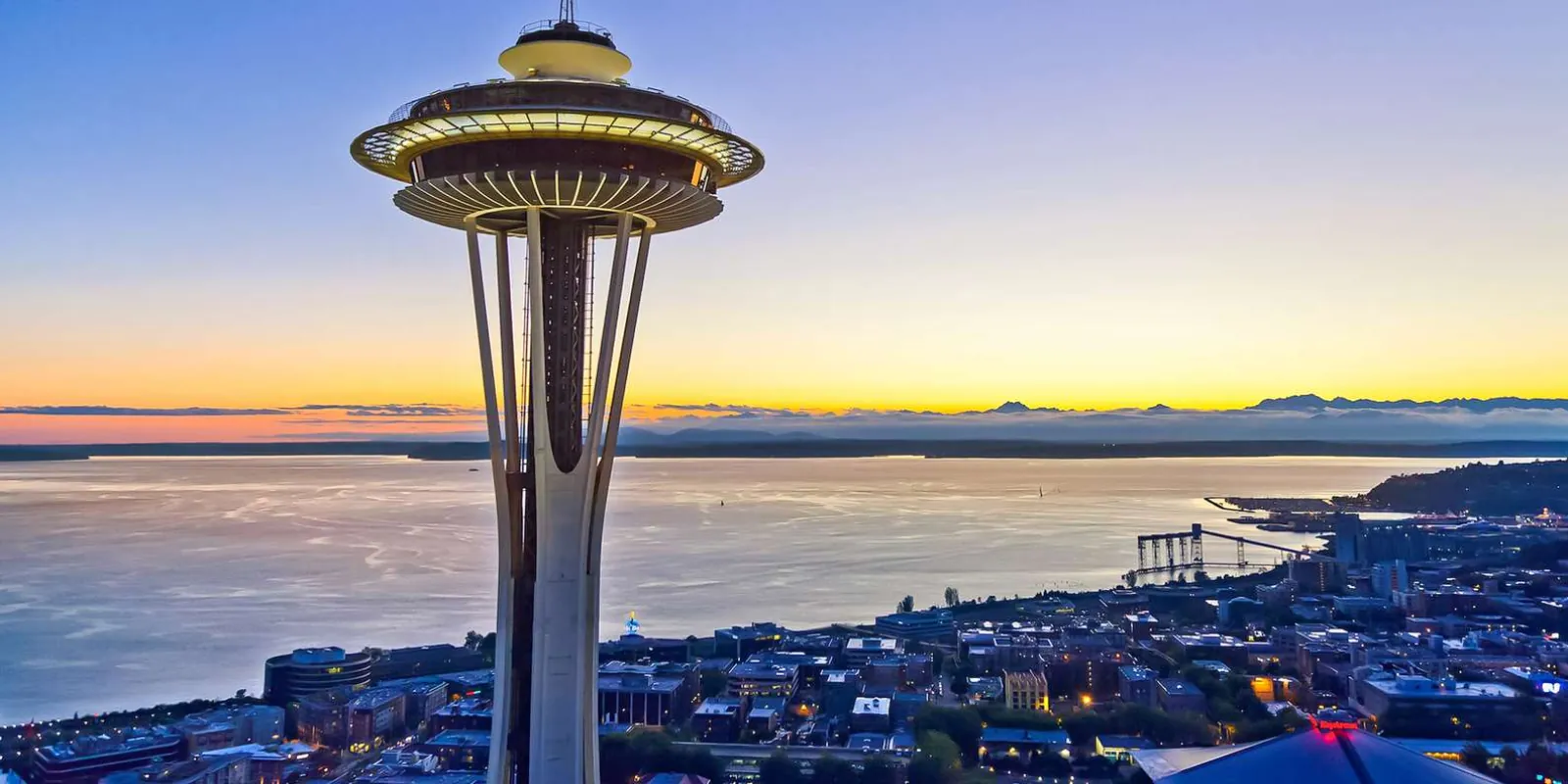 The Space Needle at dusk above Elliott Bay, lit against a violet sky