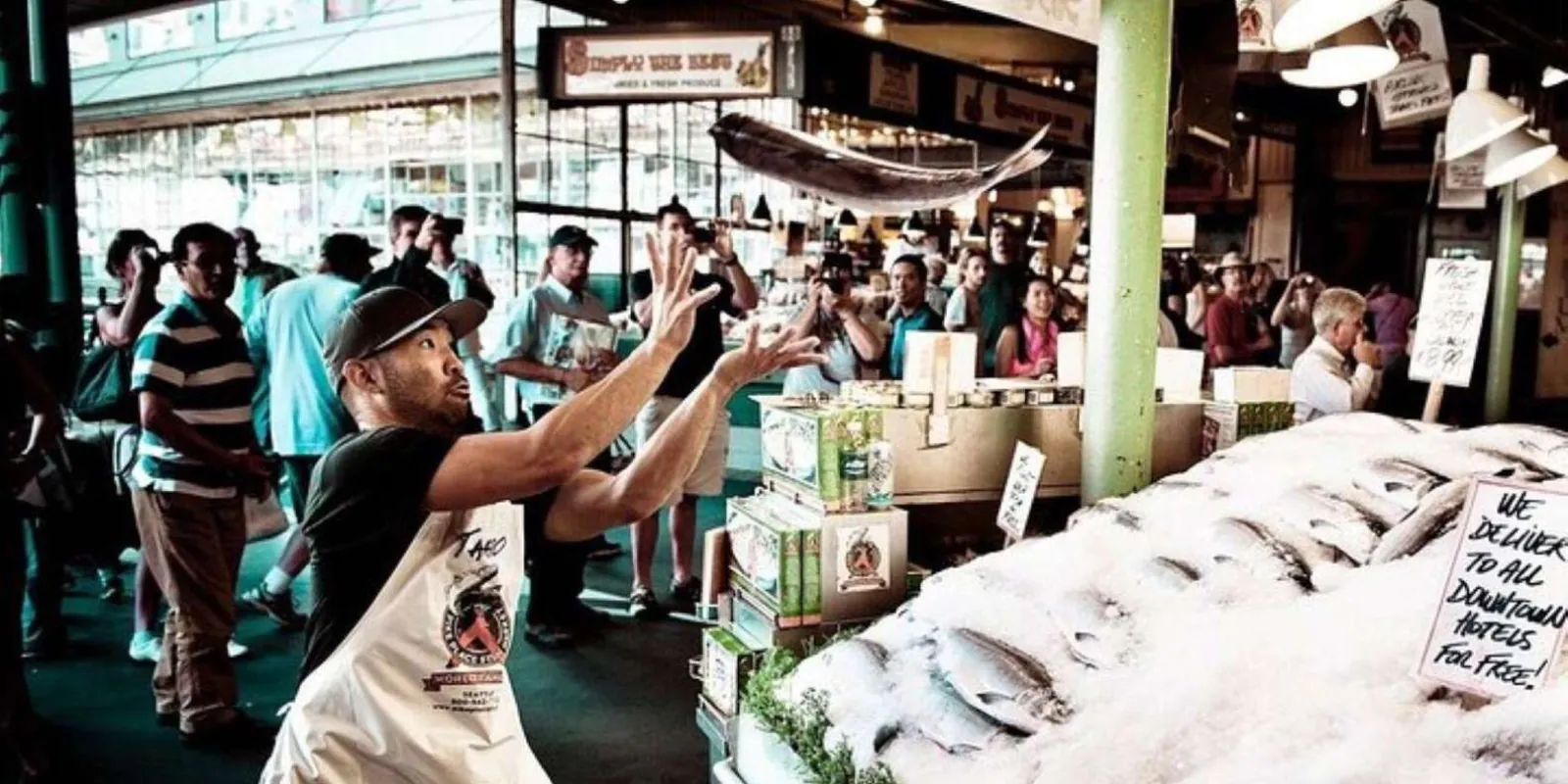 A fishmonger mid-throw over the crushed ice at the Pike Place fish counter