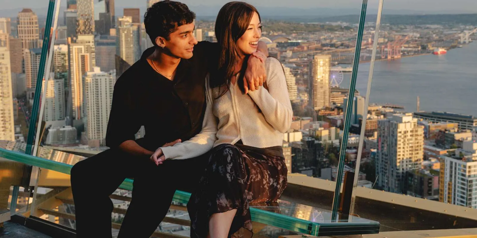Two visitors on the tilting glass benches of the Space Needle's open-air observation deck